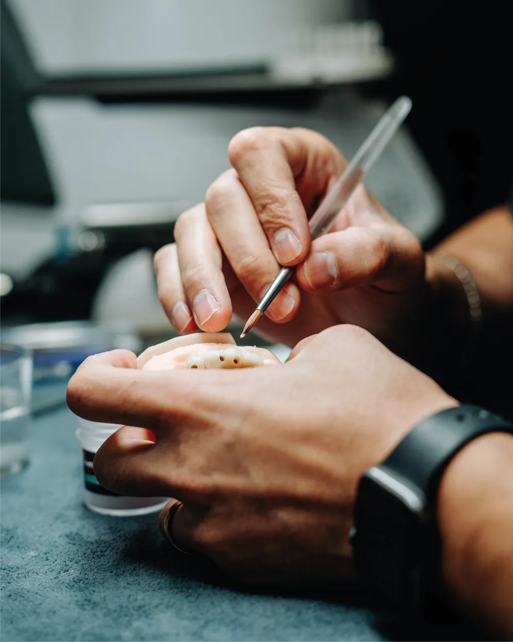 Técnico em prótese caracterizando uma lente de porcelana